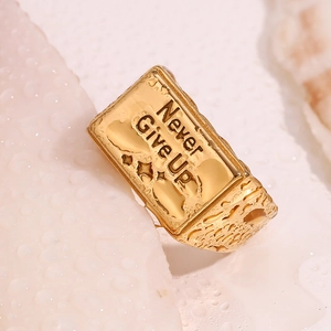 Détail macro d'une bague plaquée or 18 carats avec texte Never Give Up et texture martelée