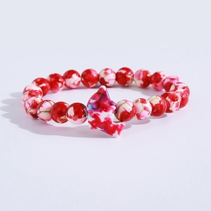 Detail of red and white marbled beaded bracelet with a colorful dolphin charm