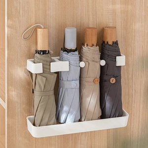 Wall-mounted white umbrella storage rack with four slots for folding umbrellas in home entryway
