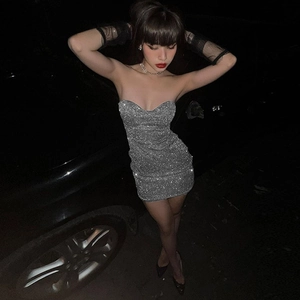 Détail d'une robe argentée à paillettes montrant la texture du tissu et le col en V sexy