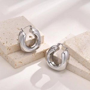 Polished silver stainless steel hollow hoop earrings set on stone display stand
