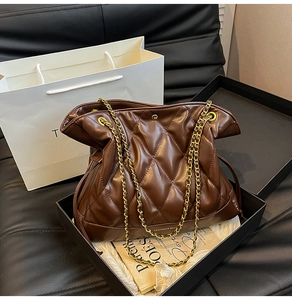 Detail of brown quilted shoulder bag with gold chain strap in a premium gift box