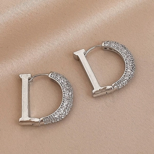 Silver D-letter hoop earrings with pavé zircons on premium silk background