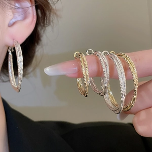 Detailed view of large textured hoop earrings in gold and silver finish shown on model