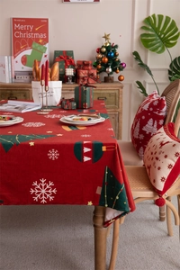 Close-up of red velvet Christmas tablecloth with white snowflakes and reindeer prints