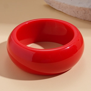 Detail of glossy bright red resin chunky bangle with elegant geometric round design