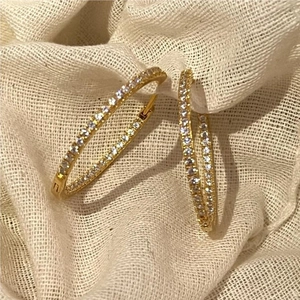 Elegant gold-plated 925 sterling silver hoop earrings with white zircon stones on fabric