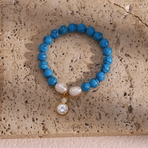Detail of beaded bracelet with blue turquoise, baroque pearls and zircon gold pendant