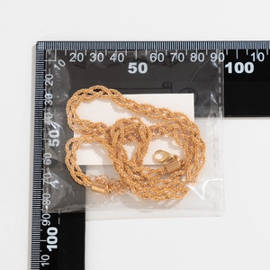 Detailed view of gold layered chain necklace with lobster clasp and extension chain on ruler