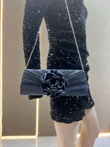 Black pleated evening clutch bag with elegant fabric rose and silver chain strap.