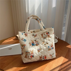 Detailed macro of a quilted cotton handbag featuring bunny illustrations and fabric label