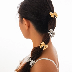 Elegant gold and silver metallic bow hair ties for women styled on a low ponytail