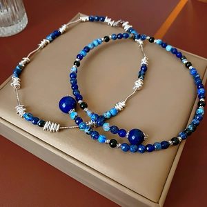 Detail of beaded necklaces featuring blue lapis beads and silver spiral wire accents