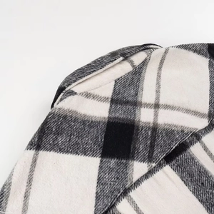 Close-up van zwart-wit geruite wollen textuur op de schouder van een warme winterjas