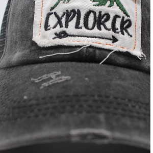 Detail of distressed baseball cap featuring Explorer embroidery and frayed brim texture