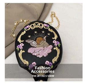 Detailed embroidery of a sleeping angel with golden stars on black baroque bag
