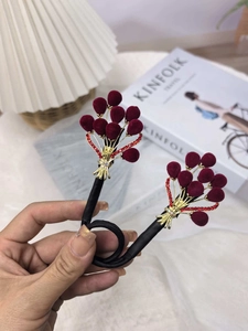 Détail d'accessoires cheveux fleurs en velours bordeaux avec tiges dorées et strass