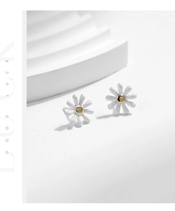 Macro detail of S925 silver daisy stud earrings with white enamel petals and golden core