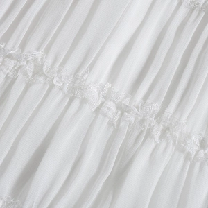 Macro detail of white pleated chiffon fabric texture with delicate lace embroidery trim