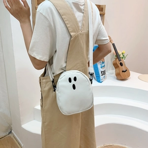Vue détaillée d'un sac bandoulière blanc avec motif visage de fantôme porté par un modèle