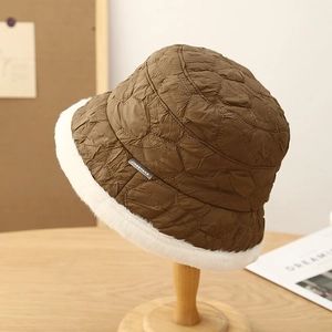 Brown quilted bucket hat with white faux fur trim on a wooden display stand