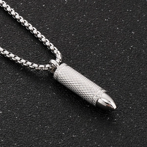 Detailed close-up of a silver bullet pendant with diamond knurled texture on a box chain