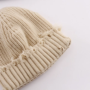 Detail shot of beige knitted beanie featuring unique distressed edges and thick yarn texture