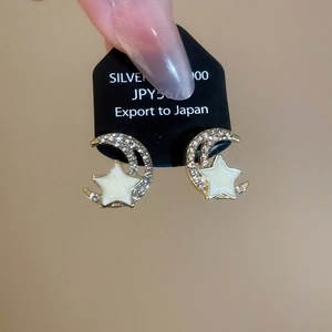Detailed view of elegant gold-plated star and moon earrings with sparkling white crystals