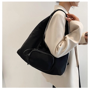 Detail of minimalist black nylon shoulder bag with a small matching oval pouch accessory