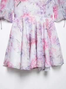 Détail d'une robe en mousseline fleurie rose avec manches bouffantes et ourlet plissé