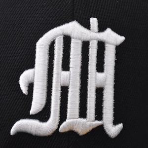 Detailed macro view of high-quality white 3D embroidery on a black cotton baseball cap
