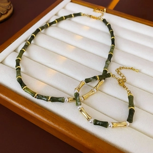 Detailed macro view of bamboo style jade and gold necklace set on a wood display
