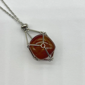 Detailed macro view of red agate gemstone inside silver stainless steel mesh cage pendant