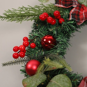 Christmas wreath with green eucalyptus leaves, red berries, and checkered bow decoration