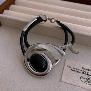 Detail of silver spiral bracelet with black oval gemstone on beige jewelry box