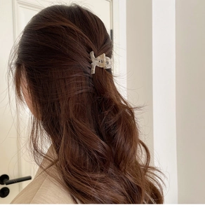 Detail of elegant acetate hair claw clip styling a half-up ponytail on wavy brown hair