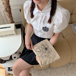 Floral embroidery canvas cosmetic bag held by a woman in a white puff-sleeve shirt