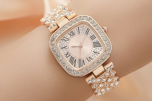 Close-up of rose gold square watch with crystal embellishments and Roman numeral dial