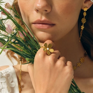Detailed view of 18k gold floral jewelry set with white pearls on a female model