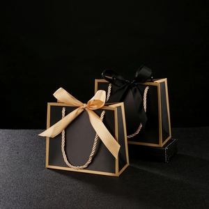 Detail of luxury black gift bags with gold trim and elegant ribbon bow handles
