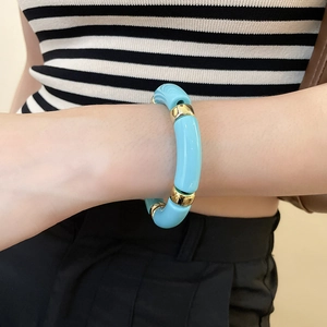 Close-up of sky blue acrylic bead and gold metal spacer ring bracelet worn on wrist