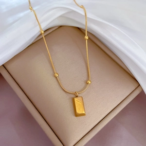 Golden titanium steel snake chain with gold beads and rectangular bar pendant in a jewelry box