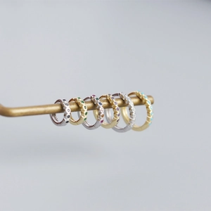 Macro detail of S925 sterling silver huggie earrings set with colorful gemstones