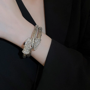Close-up of sparkling crystal-paved silver snake bracelet on a model wearing black suit