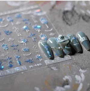 Macro detail of embossed blue floral nail art stickers with 3D texture and metallic luster