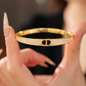 Detail shot of gold-plated bangle with CD logo and micro-paved cubic zirconia accents