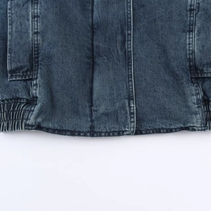 Detail of vintage blue denim jacket featuring elastic hem and premium stitching texture