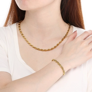 Close-up of a gold stainless steel oval link necklace and bracelet set on a model