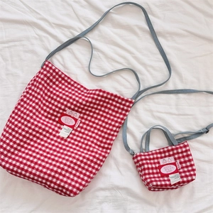 Detailed top view of red and white checkered tote bag set on white fabric texture