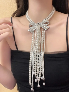 Close-up of multi-layer pearl necklace with rhinestone bow and dangling pearl tassels